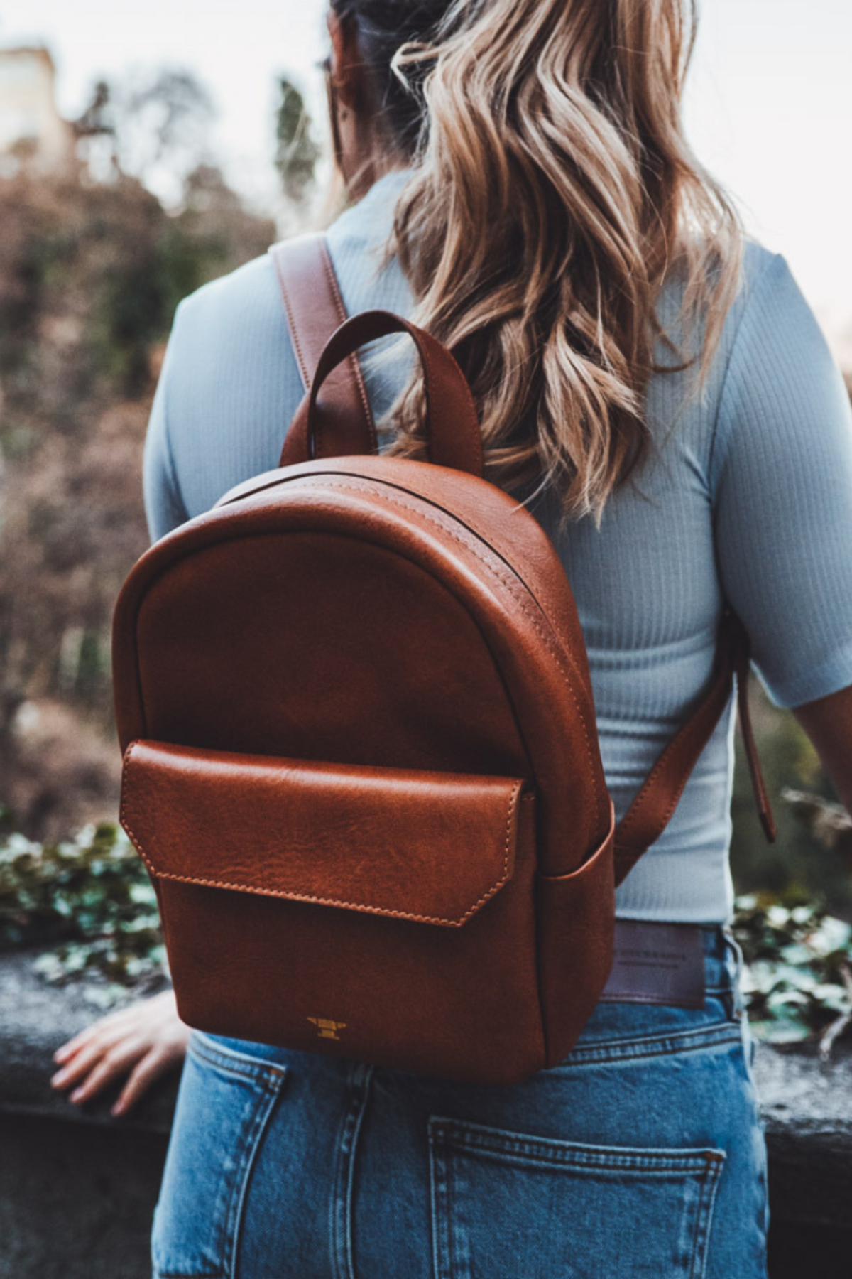 Frau von hinten trägt kleinen, braunen Leder-Rucksack mit Reissverschluss