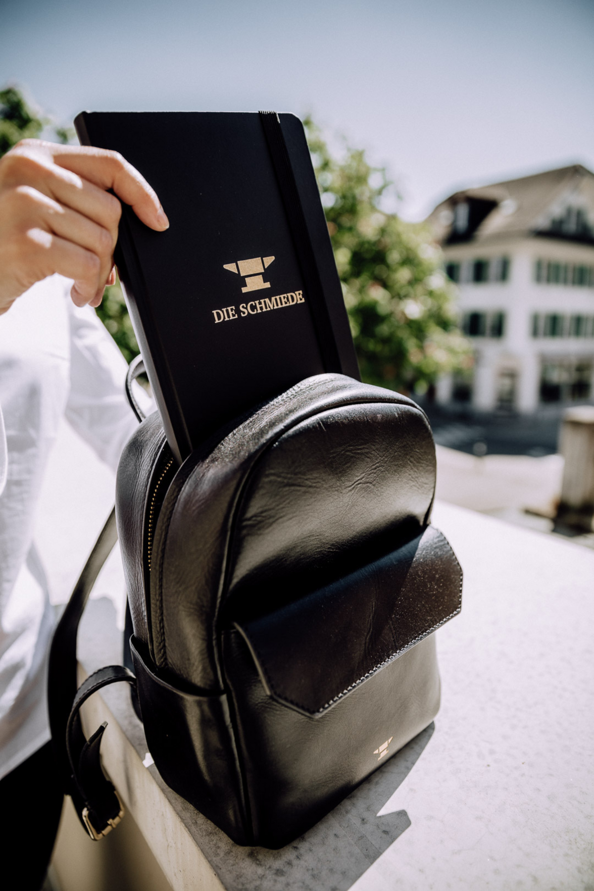A5 grosses, schwarzes Notizbuch wird in kleinen schwarzen Leder-Rucksack gepackt