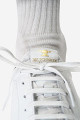 Weisser Leder-Sneaker mit Baumwoll-Schnürsenkel und dezenten goldenen Details auf der Schuhzunge