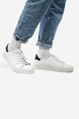 Weisser, tiefer Unisex-Sneaker aus Leder, schwarze Fersenpartie, kombiniert mit Jeans und weissen Freizeit Socken
