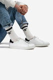 Tiefer, weisser Leder-Sneaker für Damen und Herren, kombiniert mit Jeans und weissen Baumwoll-Socken mit schwarzem Amboss